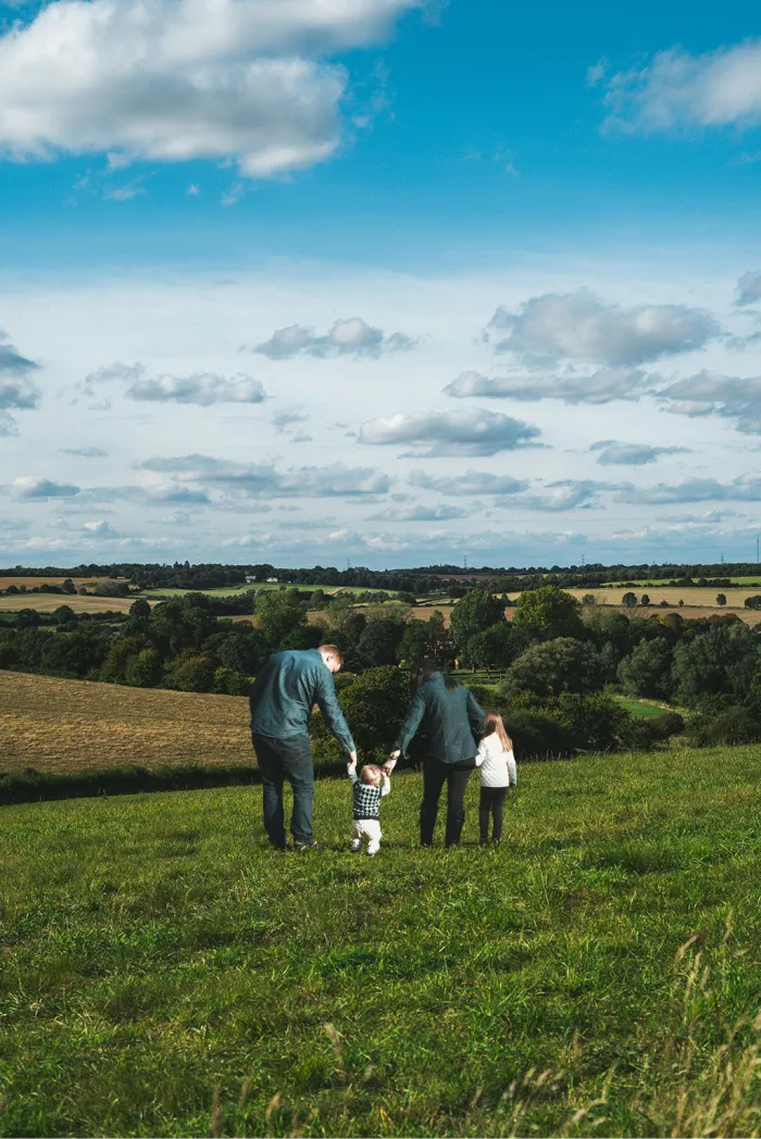Familia disfrutando de un paseo en terrenos verdes y amplios con vistas panorámicas, ideal para proyectos residenciales en entornos naturales.