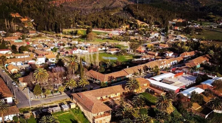 Vista aérea del pintoresco pueblo de Vichuquén, ubicado en la comuna de Vichuquén, en la Región del Maule, Chile, con sus características construcciones de tejas, arquitectura tradicional y rodeado de abundantes palmeras y árboles que realzan su encanto natural.